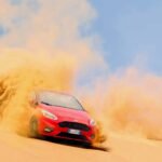 red ford focus vehicle driving on sand under blue daytime sky